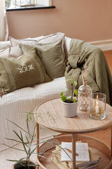 Rundt rattan sidebord med hylde i stue ved sofa og planter