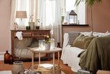 Rundt rattan sidebord med hylde i stue ved sofa og planter